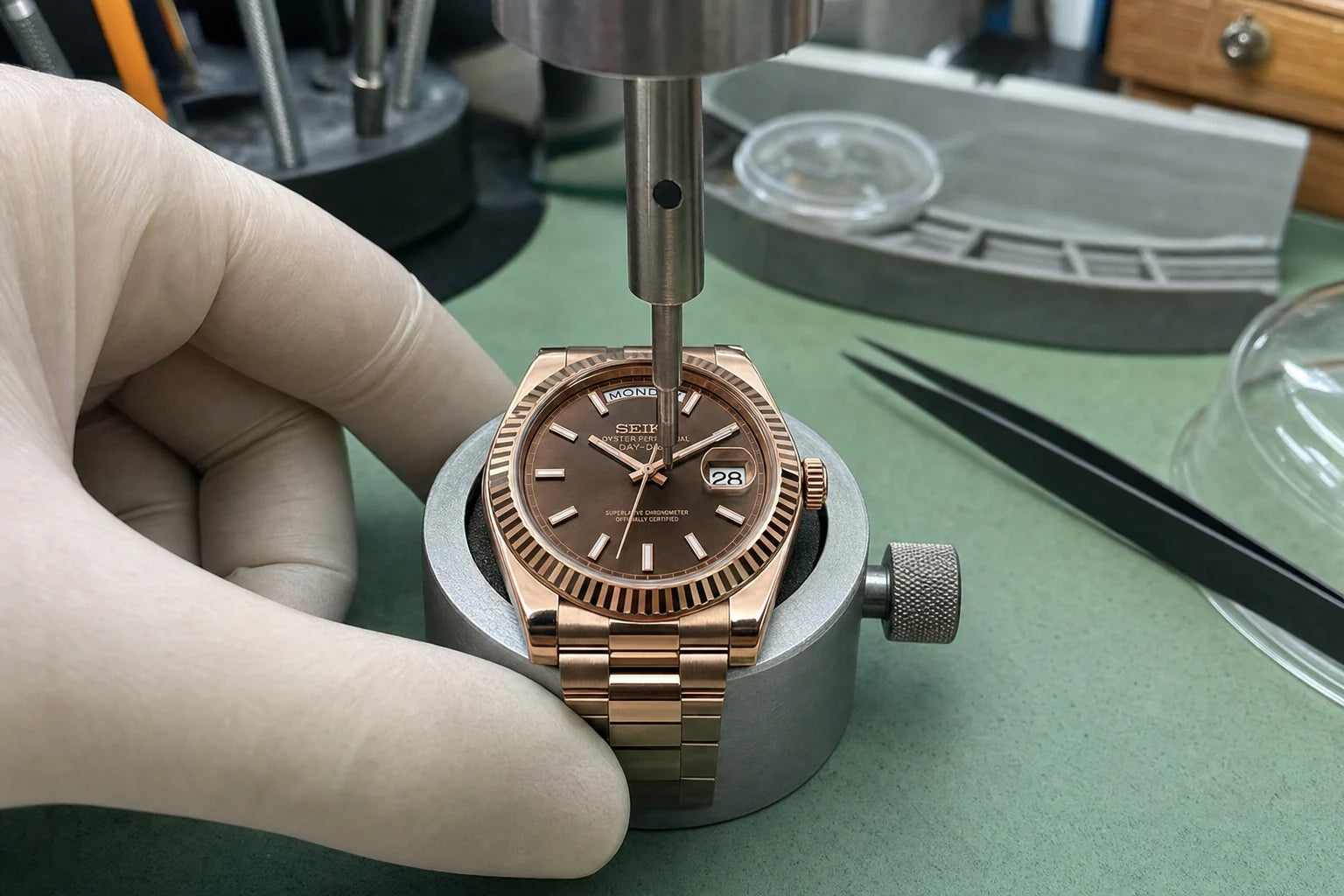 Watchmaker setting the hands at the centre of a rose-gold watch dial